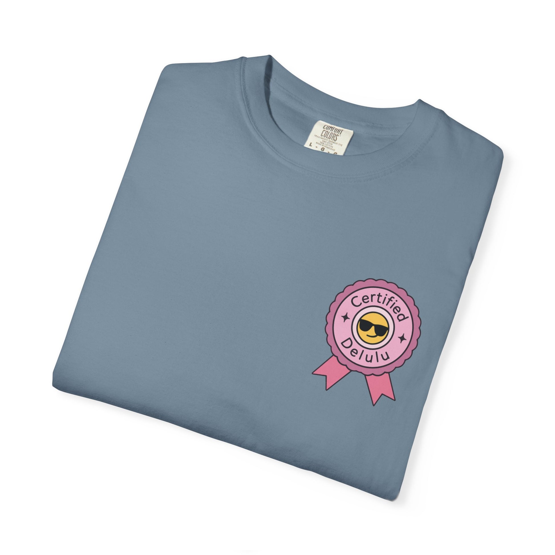 Charming portrayal of the Certified Delulu Badge Comfort Tee amidst colorful decor, perfect for outfit inspiration and casual vibes.